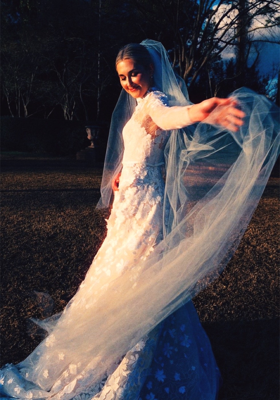 A bride twirls at dusk under warm flash against a deep blue sky, the grain and tungsten warmth of CineStill 800T.