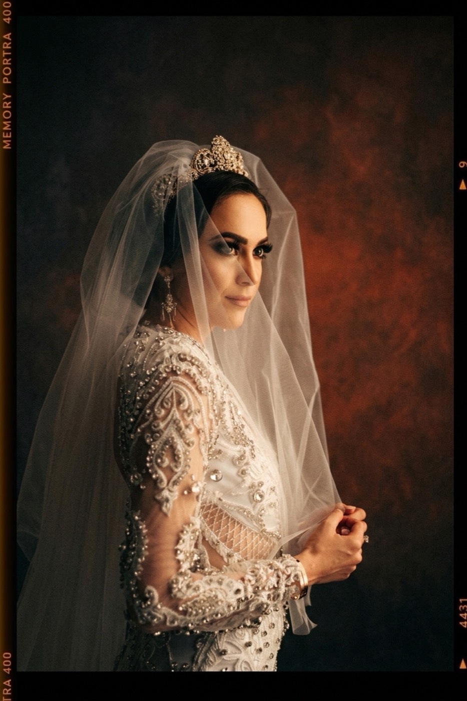 Portra 400 warmth over a painted backdrop. The beadwork and veil keep their separation.